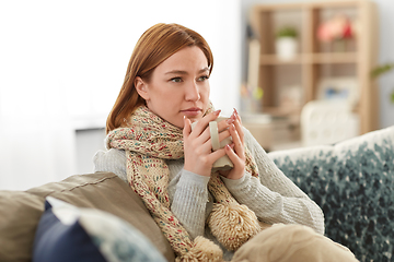 Image showing sad sick young woman drinking hot tea at home