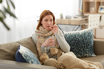 Image showing sick woman taking medicine with water at home