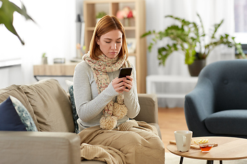 Image showing sad sick woman in scarf with smartphone at home