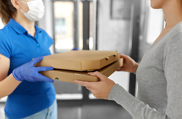 Image showing delivery girl in mask giving pizza boxes to woman