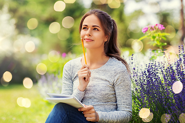 Image showing young woman writing to notebook at summer garden