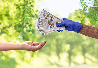 Image showing close up of hand in medical glove giving money