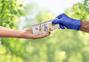 Image showing close up of hand in medical glove giving money