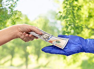 Image showing close up of hand in medical glove giving money