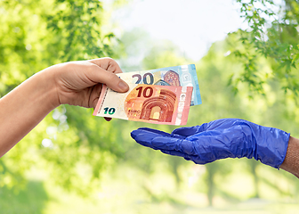 Image showing close up of hand in medical glove giving money