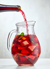 Image showing red wine pouring into jug of cutted fruits