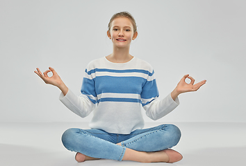 Image showing smiling teenage girl meditating in lotus pose