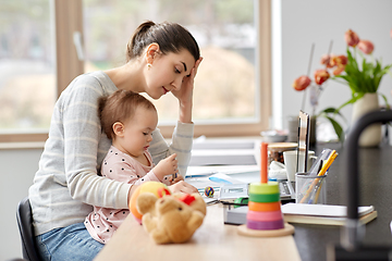 Image showing tired mother with baby working at home office