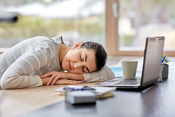 Image showing tired woman sleeping on table with laptop at home