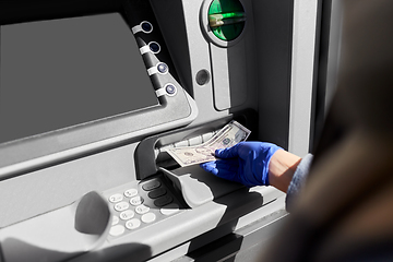 Image showing hand in medical glove with money at atm machine