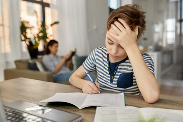 Image showing student boy with book writing to notebook at home