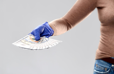 Image showing close up of hand in medical glove with money