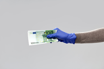 Image showing close up of hand in medical glove with money