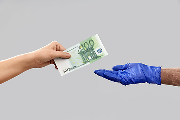 Image showing close up of hand in medical glove giving money