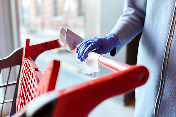 Image showing hand cleaning shopping cart handle with wet wipe