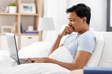 Image showing worried indian man with laptop in bed at home