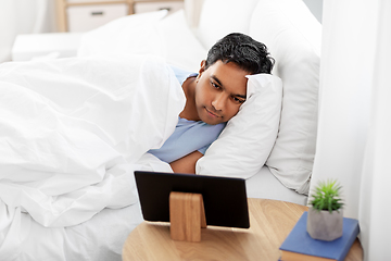 Image showing happy indian man with tablet pc in bed at home