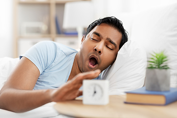 Image showing sleepy indian man with alarm clock in bed yawing