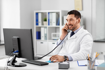 Image showing male doctor calling on desk phone at hospital