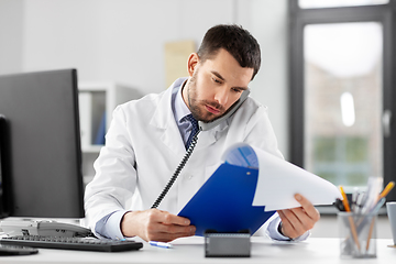 Image showing male doctor calling on desk phone at hospital