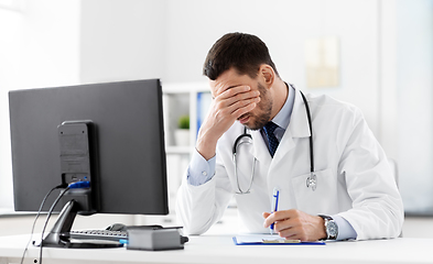 Image showing stressed male doctor with clipboard at hospital