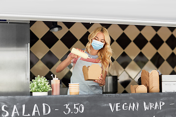 Image showing saleswoman in mask making wok at food truck