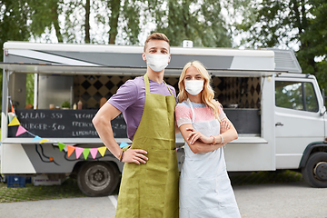 Image showing couple of young sellers in masks at food truck