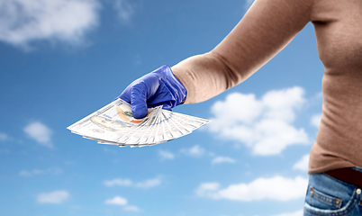 Image showing close up of hand in medical glove with money