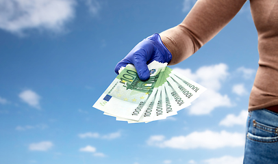 Image showing close up of hand in medical glove with money