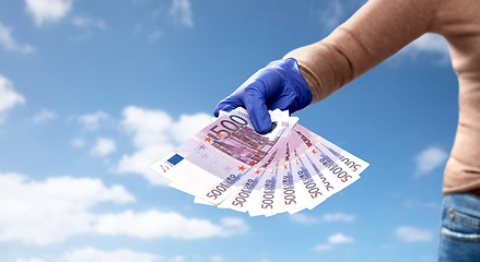 Image showing close up of hand in medical glove with money