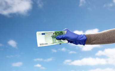 Image showing close up of hand in medical glove with money