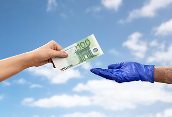 Image showing close up of hand in medical glove giving money