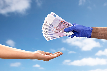 Image showing one hand in medical glove giving money to another