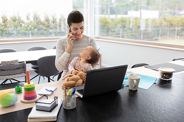 Image showing mother with baby working on laptop at home office
