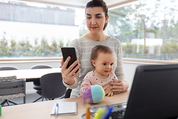 Image showing mother with baby and phone working at home office