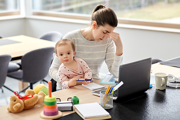 Image showing tired mother with baby working at home office