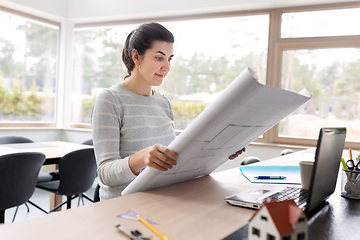 Image showing young woman with blueprint working at home office
