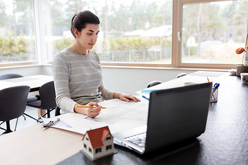 Image showing young woman with blueprint working at home office