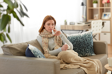 Image showing sick woman using nasal spray at home