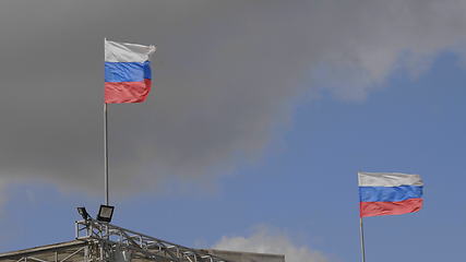 Image showing Russian flag on the flagpole waving in the wind against a blue sky with clouds