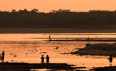 Image showing Asian women fishing in the river, silhouette at sunset