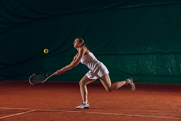 Image showing Young caucasian professional sportswoman playing tennis on sport court background