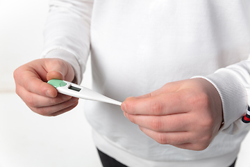 Image showing How coronavirus changed our lives. Close up of male hands holding thermometer, taking temperature on white background