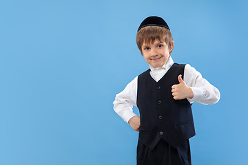 Image showing Portrait of a young orthodox jewish boy isolated on blue studio background, meeting the Passover