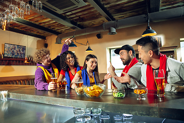 Image showing Sport fans cheering at bar, pub and drinking beer while championship, competition is going