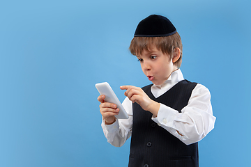 Image showing Portrait of a young orthodox jewish boy isolated on blue studio background, meeting the Passover