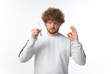 Image showing How coronavirus changed our lives. Young man checking, taking temperature on white background