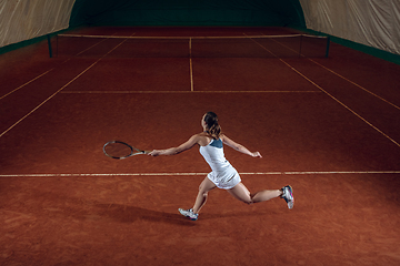 Image showing Young caucasian professional sportswoman playing tennis on sport court background