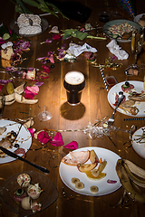 Image showing Early morning after the party. Glass of dark, cold stout, beer on the table with confetti and serpentine, leftovers, flower petals