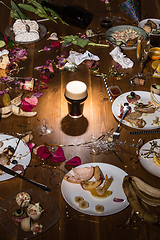 Image showing Early morning after the party. Glass of dark, cold stout, beer on the table with confetti and serpentine, leftovers, flower petals